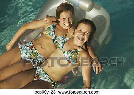 Twin Caucasian teenage girls relax on a swimming pool inflatable. View Large Photo Image Stock Image - Twin Caucasian teenage girls relax on a swimming pool inflatable.. Fotosearch