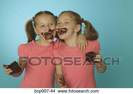 Twin girls eating chocolate cake. View Large Photo Image Picture - Twin girls eating chocolate cake.. Fotosearch