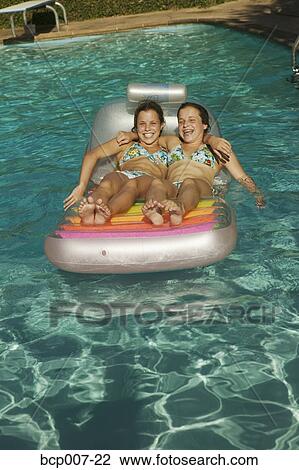 Twin teen girls floating in a pool. View Large Photo Image Stock Image - Twin teen girls floating in a pool.. Fotosearch