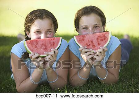 Twin teenage girls holding watermelon slices. View Large Photo Image Stock Image - Twin teenage girls holding watermelon slices.. Fotosearch