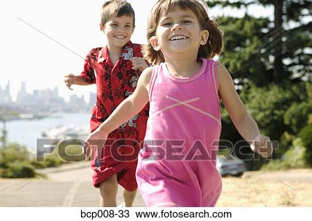 A young boy runs after his little sister. View Large Photo Image Stock Image - A young boy runs after his little sister.. Fotosearch