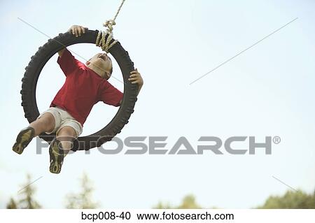 Boy flying high on a tire swing. View Large Photo Image Stock Image - Boy flying high on a tire swing.. Fotosearch