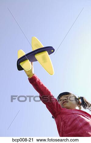 Girl flying her toy airplane through a pale blue sky. View Large Photo Image Stock Image - Girl flying her toy airplane through a pale blue sky.. Fotosearch