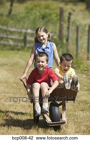 Twin boys riding in a wheelbarrow pushed by their older sister. View Large Photo Image Stock Image - Twin boys riding in a wheelbarrow pushed by their older sister.. Fotosearch