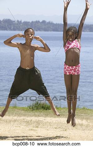 Young African-American boy and girl jump in park by lake. View Large Photo Image Stock Image - Young African-American boy and girl jump in park by lake.. Fotosearch