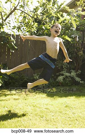 Young boy leaping in his backyard. View Large Photo Image Stock Photo - Young boy leaping in his backyard.. Fotosearch