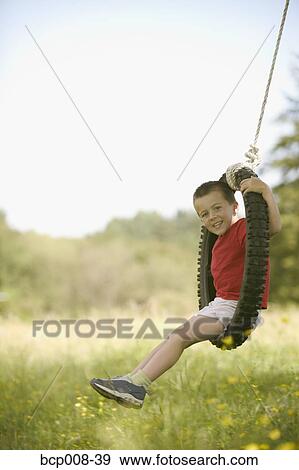 Young boy on a tire swing in the country. View Large Photo Image Stock Photo - Young boy on a tire swing in the country.. Fotosearch