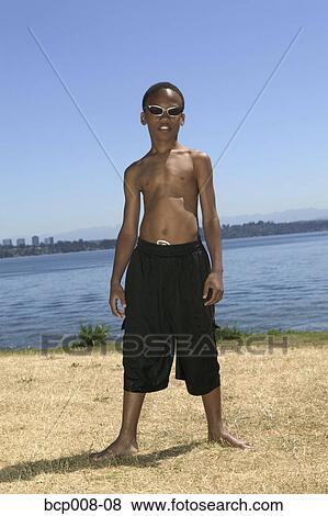 Young boy standing near a lake. View Large Photo Image Stock Photo - Young boy standing near a lake.. Fotosearch