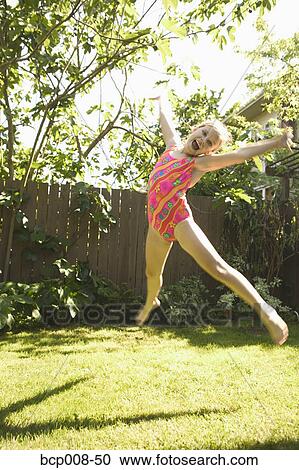 Stock Image - Young girl in a swimming suit leaping in the air.. Fotosearch