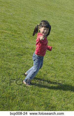 Picture - Young girl playing in grassy field.. Fotosearch