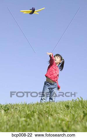 Stock Image - Young girl playing with a toy airplane.. Fotosearch