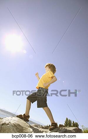 Young, red-headed Caucasian boy walks across rock pile. View Large Photo Image Stock Photograph - Young, red-headed Caucasian boy walks across rock pile.. Fotosearch