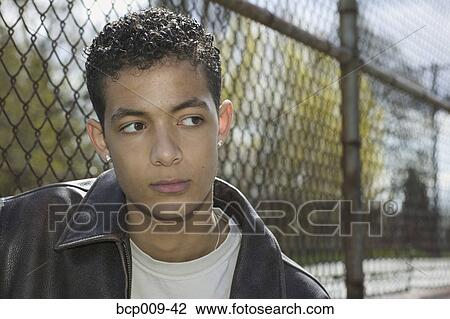 Stock Image - Portrait of a teenage boy at a fence.. Fotosearch