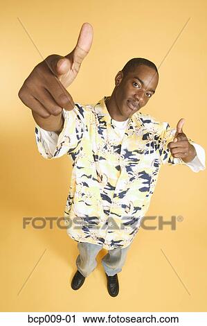 Stock Image - Teenage boy in studio portrait with yellow backdrop.. Fotosearch