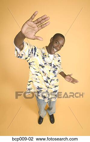 Stock Image - Teenage boy in studio portrait with yellow backdrop.. Fotosearch