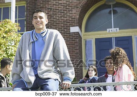 Stock Photo - Teenage boy sitting on a fence at school.. Fotosearch