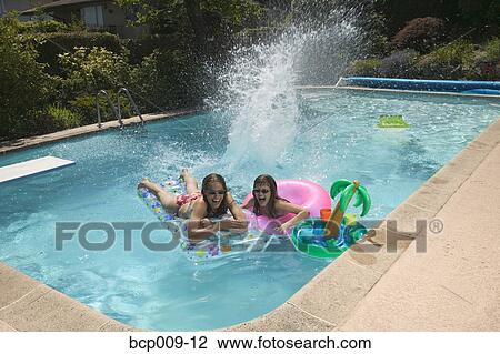 Stock Image - Teenagers playing in a swimming pool.. Fotosearch