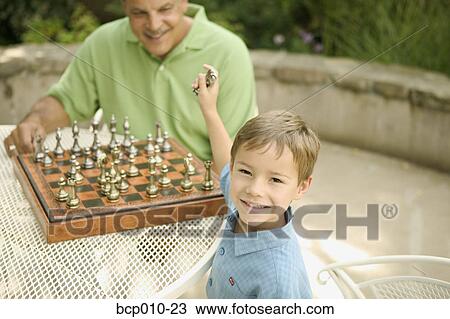 Grandfather at a chess table smiling at his young grandson. View Large Photo Image Stock Image - Grandfather at a chess table smiling at his young grandson.. Fotosearch