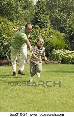 Grandfather playing with his young grandson at the park. View Large Photo Image Picture - Grandfather playing with his young grandson at the park.. Fotosearch