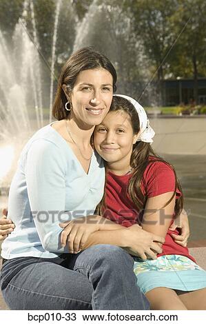 Mother hugging her daughter next to a fountain. View Large Photo Image Stock Image - Mother hugging her daughter next to a fountain.. Fotosearch