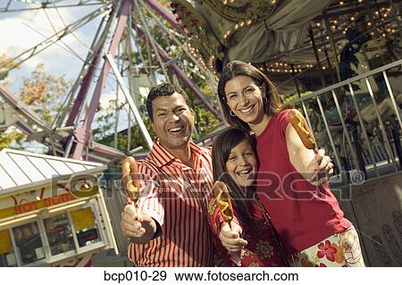 Stock Photo - Parents and daughter eating at an amusement park.. Fotosearch