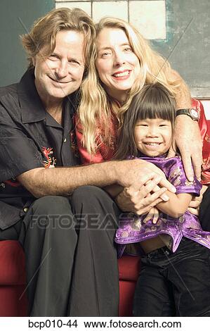 Parents hugging their young daughter. View Large Photo Image Picture - Parents hugging their young daughter.. Fotosearch