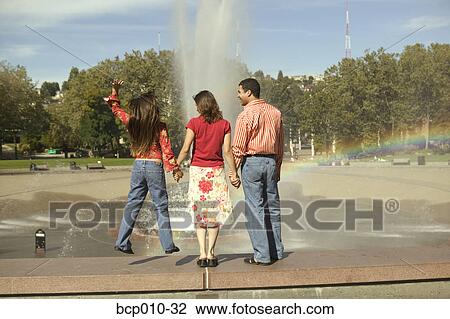 Rear view of a family watching a fountain. View Large Photo Image Stock Image - Rear view of a family watching a fountain.. Fotosearch