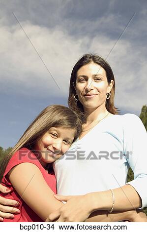 Teenage girl hugs her mother outdoors. View Large Photo Image Picture - Teenage girl hugs her mother outdoors.. Fotosearch