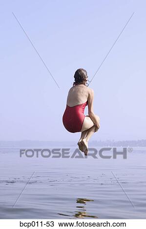 Stock Image - A woman doing a cannonball into a lake.. Fotosearch