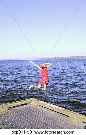 Stock Image - A woman leaping into a lake.. Fotosearch