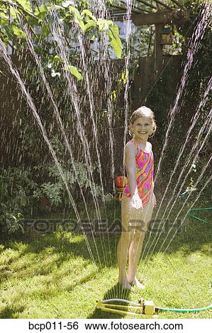 A young girl standing in a sprinkler. View Large Photo Image Stock Photograph - A young girl standing in a sprinkler.. Fotosearch