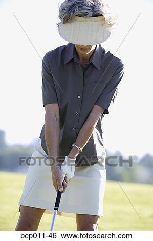 Stock Photograph - Caucasian woman in her 40s preparing to take a golf swing. Fotosearch