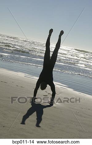 Picture - Man doing a handstand on the beach.. Fotosearch