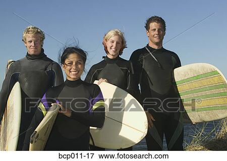 Stock Photo - Portrait of four surfers in wetsuits.. Fotosearch