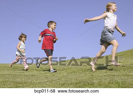 Three children running along a hillside. View Large Photo Image Stock Photo - Three children running along a hillside.. Fotosearch