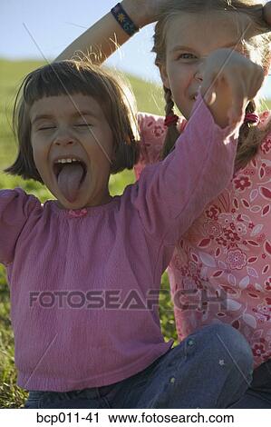 Stock Image - Two young girls making faces.. Fotosearch