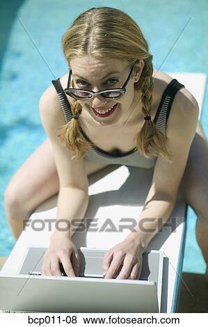 Stock Photo - Young woman with a laptop on a diving board.. Fotosearch