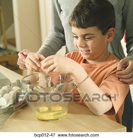 Boy mixing eggs in a bowl with mother's supervision. View Large Photo Image Stock Photo - Boy mixing eggs in a bowl with mother's supervision. . Fotosearch