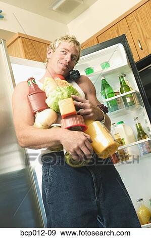 Stock Photo - Man talking on phone with his arms full of food.. Fotosearch