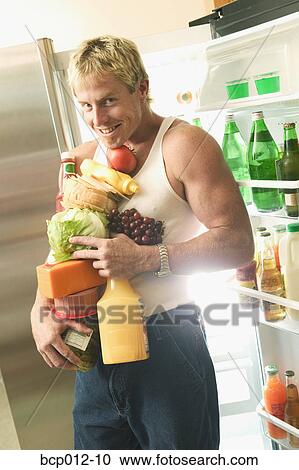 Stock Image - Man with his arms full of food.. Fotosearch