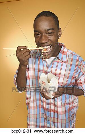 Teenage boy eating noodles from carton. View Large Photo Image Stock Image - Teenage boy eating noodles from carton.. Fotosearch
