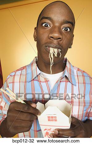Stock Image - Teenage boy eating noodles.. Fotosearch