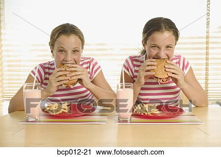 Twin teenage girls eating hamburgers. View Large Photo Image Stock Image - Twin teenage girls eating hamburgers.. Fotosearch