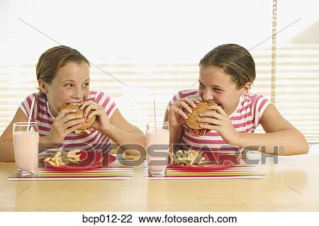 Twin teenage girls eating hamburgers. View Large Photo Image Stock Image - Twin teenage girls eating hamburgers.. Fotosearch