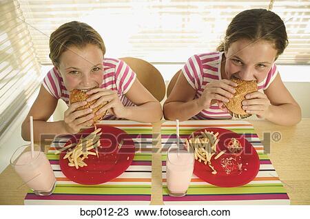 Twin teenage girls eating hamburgers. View Large Photo Image Stock Image - Twin teenage girls eating hamburgers.. Fotosearch