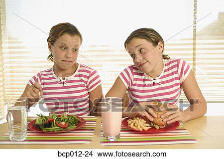 Twin teenagers eating different lunches. View Large Photo Image Picture - Twin teenagers eating different lunches.. Fotosearch