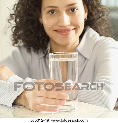 Woman holding a glass of water on a table. View Large Photo Image Stock Photo - Woman holding a glass of water on a table. . Fotosearch