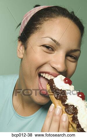 Young woman eating an eclair pastry. View Large Photo Image Stock Photo - Young woman eating an eclair pastry.. Fotosearch