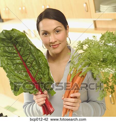 Young woman holding chard and carrots. View Large Photo Image Stock Image - Young woman holding chard and carrots.. Fotosearch
