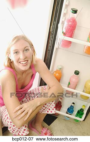 Stock Photo - Young woman sitting in a refrigerator.. Fotosearch